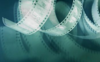 Film enroulé avec bandes de pellicule et éclats de lumière sur fond sombre